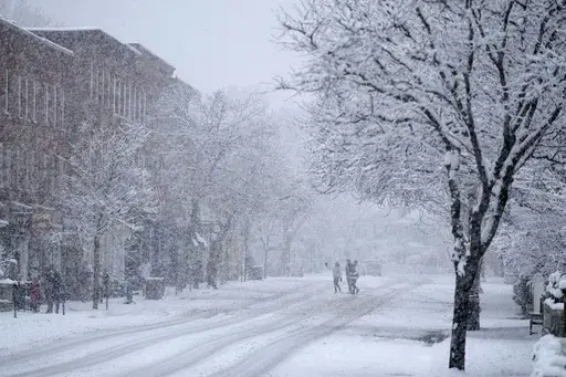 Holiday visitors walk in downtown Woodstock, Vt., during a Thanksgiving Day snowstorm, Thursday, Nov. 28, 2024. (AP Photo/Robert F. Bukaty)