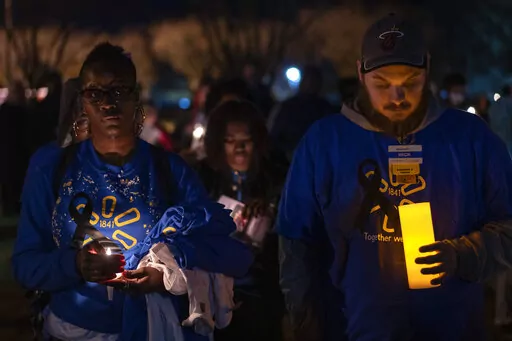 Walmart employees stand together during a candlelight vigil at Chesapeake City Park in Chesapeake, Va., Monday, Nov. 28, 2022, for the six people killed at a Walmart in Chesapeake, Va., when a manager opened fire with a handgun before an employee meeting last week. (AP Photo/Carolyn Kaster)