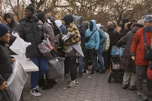 Migrants pick up blankets near a Migrant Assistance Center at St. Brigid Elementary School on Tuesday, Dec. 5, 2023, in New York. Mayor Eric Adam's office on Tuesday, April 9, 2024, said New York City will end its relationship with a medical services company tasked with housing and caring for an influx of international migrants, following scrutiny over the company's lucrative deal with the city and the quality of its humanitarian services. (AP Photo/Andres Kudacki, File)