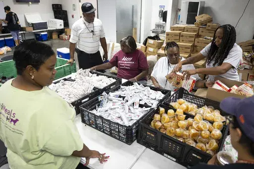 Meals on Wheels employees take advantage of an assembly line to prepare bags of food for clients, Friday, July 12, 2024, in Houston. Staff deliver hot meals as well as shelf stable items to clients daily, many of whom are still without power after Hurricane Beryl. (AP Photo/Annie Mulligan)