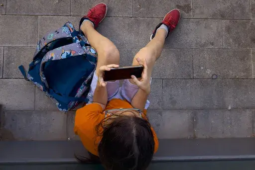 A 11-year-old boy plays with his father's phone outside school in Barcelona, Spain, Monday, June 17, 2024. (AP Photo/Emilio Morenatti, File)
