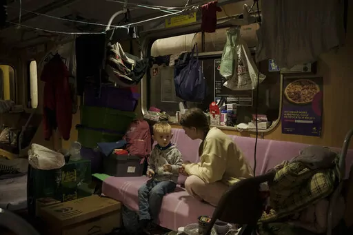 People sit inside a subway car, parked in a station being used as a bomb shelter, as Russian attacks continue in Kharkiv, Ukraine, Friday, March 25, 2022. (AP Photo/Felipe Dana)