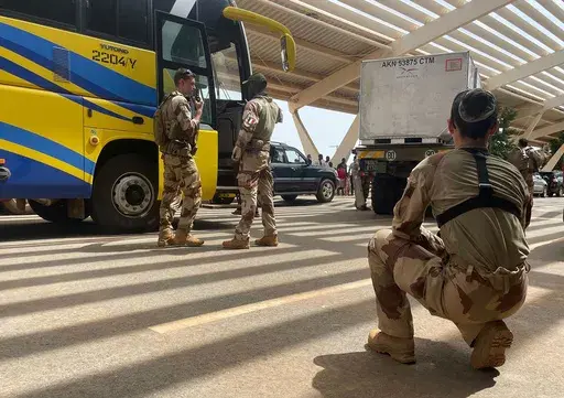 French soldiers assist mostly French nationals in a bus waiting to be airlifted back to France on a French military aircraft, at the international Airport in Niamey, Niger, Tuesday, Aug. 1, 2023. The French Foreign Ministry in Paris cited recent violence that targeted the French Embassy as one of the reasons for the evacuation. The decision comes during a deepening crisis sparked by the coup last week against Niger's democratically elected president, Mohamed Bazoum. (AP Photo/Sam Mednick)