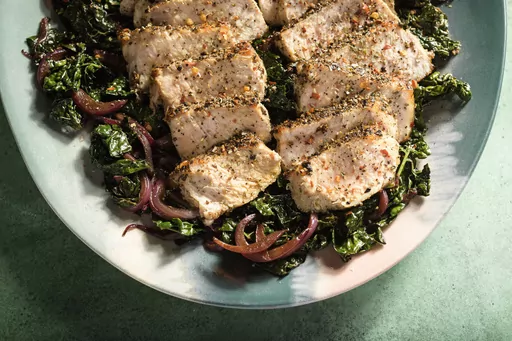 This image released by Milk Street shows a recipe for pork with kale, red wine and toasted garlic. (Milk Street via AP)