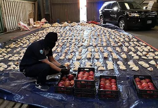 In this photo released by Saudi Press Agency, a Saudi custom officer opens imported pomegranates, as customs foiled an attempt to smuggle over 5 million pills of an amphetamine drug known as Captagon, which they said came from Lebanon, at Jiddah Islamic Port, Saudi Arabia, Friday, April 23, 2021. A little white pill has given Syrian President Bashar Assad powerful leverage with his Arab neighbors, who have been willing to bring him out of pariah status in hopes he will stop the flow of highly ad