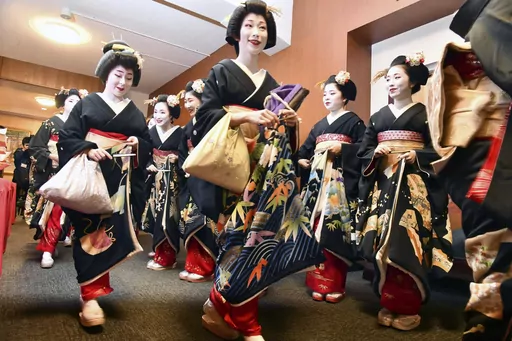 Kimono-clad "geiko" and "maiko" professional entertainers arrive for a ceremony to start this year's business in Kyoto, western Japan, on Jan. 7, 2020. Japan’s ancient capital of Kyoto, long a popular destination for tourists, will be closing off some private-property alleys in its famous geisha district, as complaints grow about misbehaving visitors. (Kyodo News via AP, File)