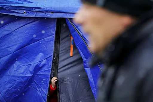 A refugee that fled the conflict from neighboring Ukraine sticks out her hand from a waiting area tent at the Romanian-Ukrainian border, in Siret, Romania, Thursday, March 3, 2022. As millions of women and children flee across Ukraine's borders in the face of Russian aggression, concerns are growing over how to protect the most vulnerable refugees from being targeted by human traffickers or becoming victims of other forms of exploitation. (AP Photo/Andreea Alexandru)