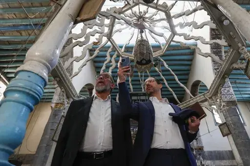Rabbi Yusuf Hamra, left, and his son Henry take pictures as they visit the Al-Raqi synagogue in the old city of Damascus Feb. 18, 2025. The Syrian-American Jewish family returned for the first time since emigrating from Syria to the United States more than three decades ago. (AP Photo/Omar Sanadiki, File)