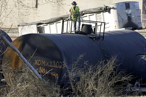 A cleanup worker stands on a derailed tank car of a Norfolk Southern freight train in East Palestine, Ohio, continues, Feb. 15, 2023. The fire that erupted after last month's train derailment in Ohio melted a key part of the tank cars filled with toxic chemicals, so federal officials warned railcar owners Thursday, March 2, 2023, to check their fleets for similar flaws. (AP Photo/Gene J. Puskar, File)
