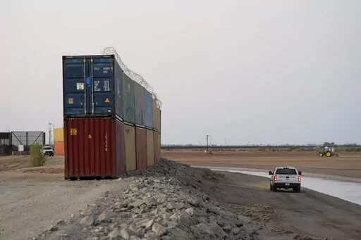 Border Patrol agents patrol along a line of shipping containers stacked near the border on Aug. 23, 2022, near Yuma, Ariz. The Cocopah Indian Tribe is welcoming the federal government's call for the state of Arizona to remove a series of double-stacked shipping containers placed along the U.S.-Mexico border near the desert city of Yuma, saying they are unauthorized and violate U.S. law. (AP Photo/Gregory Bull, File)