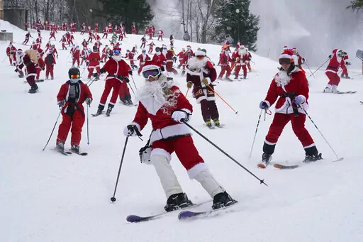 Skiers dressed in Santa Claus outfits hit the slopes for charity at the Sunday River Ski Resort, Sunday, Dec. 11, 2022, in Newry, Maine. (AP Photo/Robert F. Bukaty)