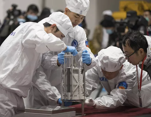 In this Thursday, Dec. 17, 2020 photo provided by China's Xinhua News Agency, technicians prepare to weigh a container carrying moon samples retrieved by China's Chang'e 5 lunar lander in Beijing. In a report published in the journal Nature Geoscience on Monday, March 27, 0223, scientists announced they have discovered a new and renewable source of water on the moon for future explorers in the lunar samples. Water was embedded in tiny glass beads in the lunar dirt where meteorite impacts occur. 