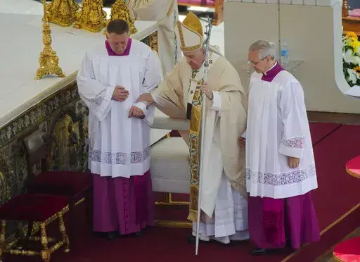 Pope Francis is helped walking as he celebrates the canonization mass for ten new saints in St. Peter's Square at The Vatican, Sunday, May 15, 2022. Francis created ten new saints on Sunday, rallying from knee pain that has forced him to use a wheelchair to preside over the first canonization ceremony at the Vatican in over two years. (AP Photo/Gregorio Borgia)