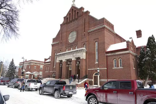 Church of the Incarnation is shown, Sunday, Jan. 23, 2022, in Minneapolis, where residents could pick up coats, sweaters and frozen chicken. With attendance dwindling, historic urban churches built in the early to mid-20th century, are fulfilling their faith-based mission to serve their neighbors. Between mass, people can pick up coats and sweaters along with bags of frozen chicken. (AP Photo/Jim Mone)