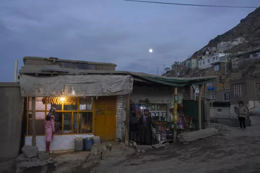 An Afghan green grocery owner stands outside his shop as a girl buy bread from a bakery, in Kabul , Afghanistan, on Wednesday, Nov. 17, 2021.Since the chaotic Aug. 15 Taliban takeover of Kabul, an already war-devastated economy once kept alive by international donations alone is now on the verge of collapse. There isn't enough money for hospitals. The World Health Organization is warning of millions of children suffering malnutrition, and the U.N. says 97% of Afghans will soon be living below th