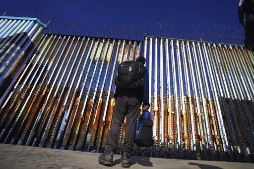 A migrant waits of the Mexican side of the border after United States Customs and Border Protection officers detained a couple of migrants crossing the US-Mexico border on the beach, in Tijuana, Mexico, Jan. 26, 2022. About 3 in 10 also worry that more immigration can cause native-born Americans to lose their economic, political and cultural influence, according to a poll by The Associated Press-NORC Center for Public Affairs Research. (AP Photo/Marco Ugarte, File)