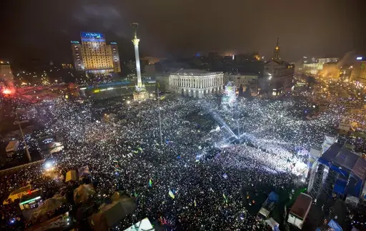 In this Jan. 1, 2014, file photo Pro-European Union activists hold lights as they sing the Ukrainian national anthem, celebrating the New Year in Kyiv's main square. At least 100,000 Ukrainians gathered in a sign of support for integration with Europe. On Nov. 21, 2023, Ukraine marks the 10th anniversary of the uprising that eventually led to the ouster of the country’s Moscow-friendly president. (AP Photo/Efrem Lukatsky, file)