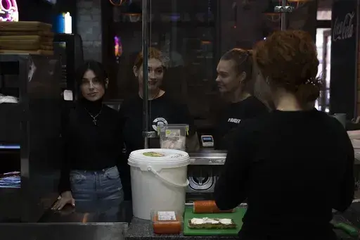 The workers of White Burger restaurant wait to take orders, in Kramatorsk, Ukraine, Wednesday, Sept. 13, 2023. The restaurant was reopened in September of the previous year following the successful counteroffensive of Ukrainian army in the Kharkiv region. (AP Photo/Hanna Arhirova)