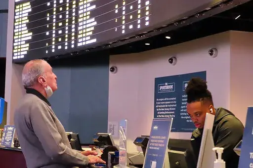 A man places a bet at the sportsbook at the Ocean Casino Resort, on Thursday, Feb. 10, 2022, in Atlantic City, N.J. The American Gaming Association estimates more than 31 million Americans will bet on this year's Super Bowl NFL football game. (AP Photo/Wayne Parry)