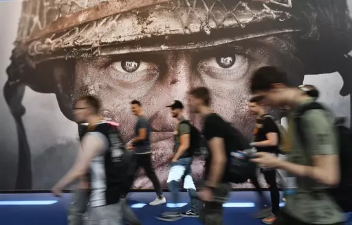 Visitors passing an advertisement for the video game 'Call of Duty' at the Gamescom fair for computer games in Cologne, Germany, on Aug. 22, 2017. The European Union on Monday approved Microsoft’s $69 billion purchase of video game maker Activision Blizzard, deciding the deal won’t stifle competition for popular console titles like Call of Duty and accepting the U.S. tech company’s remedies to boost competition in cloud gaming. (AP Photo/Martin Meissner, File)