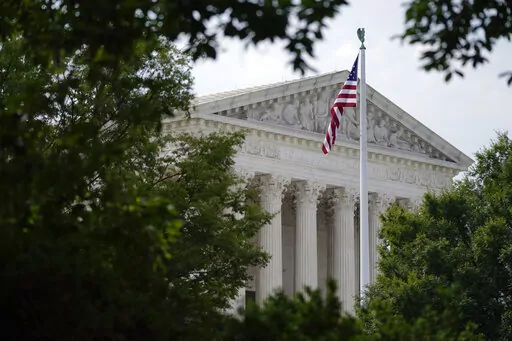 An American flag waves in front of the U.S. Supreme Court building in Washington, June 27, 2022. Supreme Court arguments are continuing long after a red light tells lawyers to stop. Arguments that usually lasted an hour have stretched beyond two this term so on many days it is well past lunchtime before the court breaks. (AP Photo/Patrick Semansky, File)