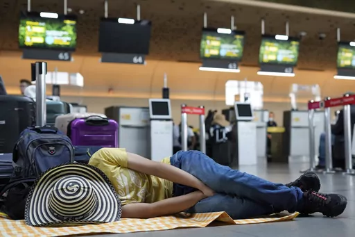 A Viva Air passenger sleeps at the airport after the low-cost airline suspended its operations at the El Dorado International Airport in Bogota, Colombia, Feb. 28, 2023. Two to three hours is generally the minimum recommended time for an international layover, but in some cases that might not even be sufficient. Account for time to clear customs and go through security again, and you might also need to retrieve and recheck luggage. (AP Photo/Fernando Vergara)