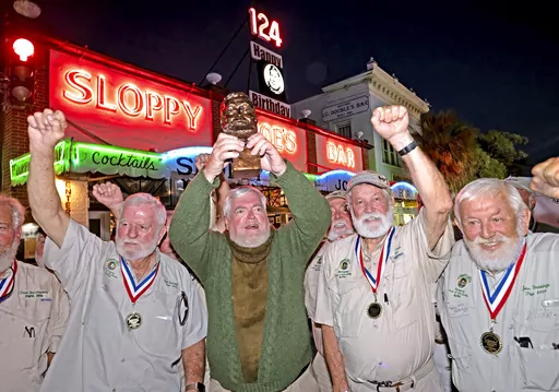 In this Saturday, July 22, 2023, photo provided by the Florida Keys News Bureau, Gerrit Marshall, center, hoists his trophy after winning the Hemingway Look-Alike Contest at Sloppy Joe's Bar in Key West, Fla. After 11 years of competing Marshall, a Madison, Wisc., resident, finally achieved success on his 68th birthday. Flanking Marshall, from left, are previous winners including Tom Grizzard, Wally Collins and John Stubbings. The competition was a highlight of the annual Hemingway Days festival