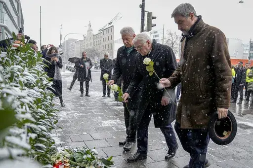 Markus Soeder, Prime Minister of Bavaria, German President Frank-Walter Steinmeier and Dieter Reiter (SPD),Mayor of Munich, from right, bring flowers to the site where a car crashed into a Ver.di demonstration the day before, Munich, Germany, Friday, Feb. 14, 2025. (AP Photo/Ebrahim Noroozi)
