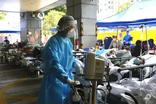 Patients in hospital beds wait in a temporary holding area outside Caritas Medical Centre in Hong Kong , Wednesday, March 2, 2022. Some people are forced to wait outside the hospital due to it currently being overloaded with possible COVID-infected patients. (AP Photo/Kin Cheung)