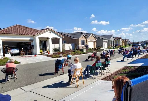 Neighbors of Lisa and Larry Neula watching them perform a Hawaiian dance in their driveway in Sacramento, Calif., in March 2022. The two began their driveway performances during lockdown and have kept them up. (John Pasamonte via AP)