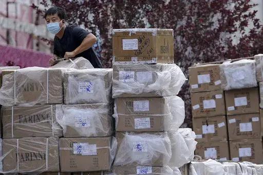 A worker loads boxes of goods from a truck outside a wholesale clothing mall in Beijing on June 14, 2022. (AP Photo/Andy Wong, File)