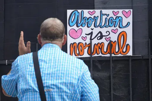 Anti-abortion activist Coleman Boyd, faces a new sign stating that "Abortion is normal," as he preaches outside the Jackson Women's Health Organization clinic in Jackson, Miss., Thursday, June 30, 2022. (AP Photo/Rogelio V. Solis)