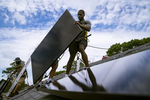 Employees of NY State Solar, a residential and commercial photovoltaic systems company, install an array of solar panels on a roof, Aug. 11, 2022, in the Long Island hamlet of Massapequa, N.Y. The Biden administration is announcing Thursday, April 20, 2023, more than $80 million in funding as part of a push to make more solar panels in the U.S. and make solar energy available in more communities. (AP Photo/John Minchillo, File)