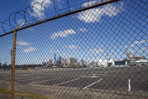 The Manhattan skyline is seen behind the parking lot and terminal of the Brooklyn Cruise Terminal on April 2, 2020, in New York. New York City is temporarily turning the Brooklyn Cruise Terminal into a shelter and services hub for asylum-seekers, Mayor Eric Adams said Saturday, Jan. 21, 2023, announcing the latest in a series of facilities the city has set up, and sometimes shut down, as it strains to handle an ongoing influx. (AP Photo/Mary Altaffer, File)