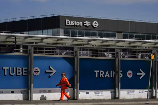 A construction worker walks past Euston station, in London, Tuesday, June 21, 2022. Tens of thousands of railway workers walked off the job in Britain on Tuesday, bringing the train network to a crawl in the country’s biggest transit strike for three decades. (AP Photo/Alberto Pezzali)