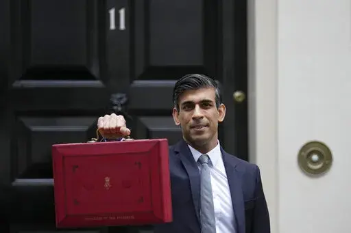 Britain's Chancellor of the Exchequer Rishi Sunak holds up the traditional ministerial red dispatch box as he leaves for the House of Commons to deliver the Budget in London, Oct. 27, 2021. Revelations that Prime Minister Boris Johnson and his staff partied while Britain was in a coronavirus lockdown have provoked public outrage and led some members of his Conservative Party to consider ousting their leader. If they manage to push Johnson out — or if he resigns — the party would hold a leade