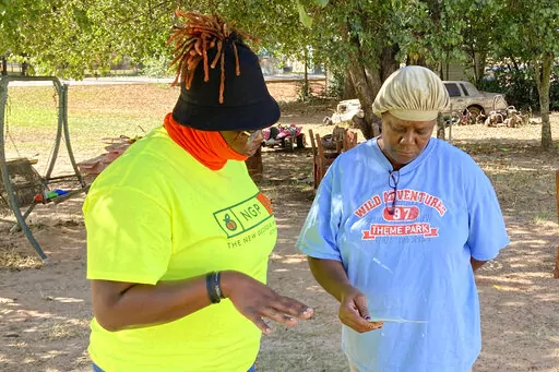 Erika Hardwick, left, a paid canvasser with the New Georgia Project Action Fund, shared literature with Patricia Lee urging Lee to vote on Wednesday, Oct. 5, 2022 in Dawson, Ga. Candidates, parties and outside groups are increasing their emphasis on door-to-door outreach as Georgia grows more politically competitive. (AP Photo/Jeff Amy)