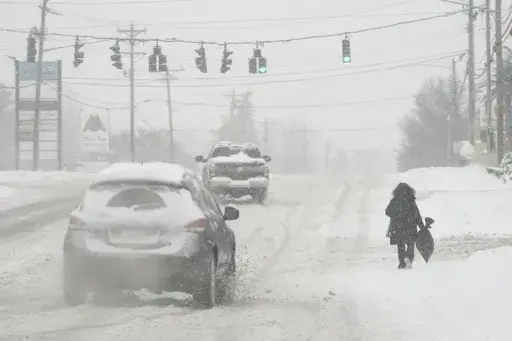 Heavy snow falls as a person walks along U.S. Route 42 in Florence, Ky., Monday, Jan. 6, 2025. (AP Photo/Carolyn Kaster, File)