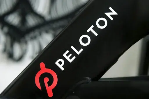 This Nov. 19, 2019 photo shows a Peloton logo on the company's stationary bicycle in San Francisco, Calif.  Peloton told employees Thursday, Oct. 6, 2022,  that it will cut approximately 500 jobs, or about 12% of its workforce, as post- pandemic sales of its indoor exercise equipment continues to tail off.  (AP Photo/Jeff Chiu, File)