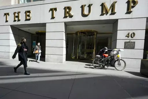 Pedestrians and a food delivery man are seen outside the Trump building on Wall Street, in New York's Financial District, March 23, 2021. (AP Photo/Mary Altaffer, File )
