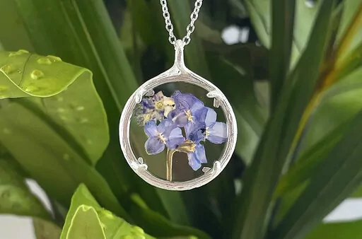 This image provided by Catherine Weitzman jewelry shows a floral necklace. Designer Catherine Weitzman says. "Nature has not only inspired my jewelry," she says. Her current collection has necklaces made of tiny alpine flowers captured in glass; earrings, cast in gold vermeil or recycled silver, of fan coral found on island beaches; and pendants of fern from the forest floor, also cast in metal. Weitzman thinks biophilia is trending because the idea of being surrounded by nature and connecting w