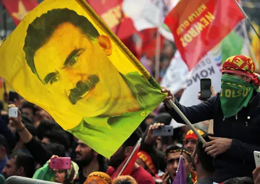 In this file photo dated Wednesday, March 21, 2018, a youth holds a flag with the image of Abdullah Ocalan, the jailed leader of the rebel Kurdistan Workers' Party, or PKK, in Istanbul, Turkey. (AP Photo/Lefteris Pitarakis, File)