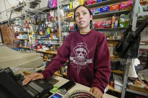 College student Jimena Sanchez, right, who studies children's development works as a part-time cashier earning minimum wage at a family store, in Los Angeles on Oct. 11, 2024. (AP Photo/Damian Dovarganes)