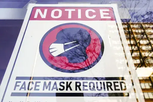 A sign requiring masks as a precaution against the spread of the coronavirus on a store front in Philadelphia, is seen Feb. 16, 2022. Philadelphia is reinstating its indoor mask mandate after reporting a sharp increase in coronavirus infections, Dr. Cheryl Bettigole, the city's top health official, announced Monday, April 11, 2022. Confirmed COVID-19 cases have risen more than 50% in 10 days, the threshold at which the city's guidelines call for people to wear masks indoors. (AP Photo/Matt Rourk