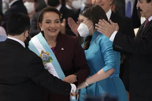 President Xiomara Castro smiles as she receives the presidential sash, as her husband former President Manuel Zelaya applauds during her inauguration ceremony, in Tegucigalpa, Honduras, Jan. 27, 2022. Castro signed a measure on Monday, April 25, 2022, to repeal a law that would allow the creation of special self-governing zones for foreign investors in Honduras. (AP Photo/Moises Castillo, File)