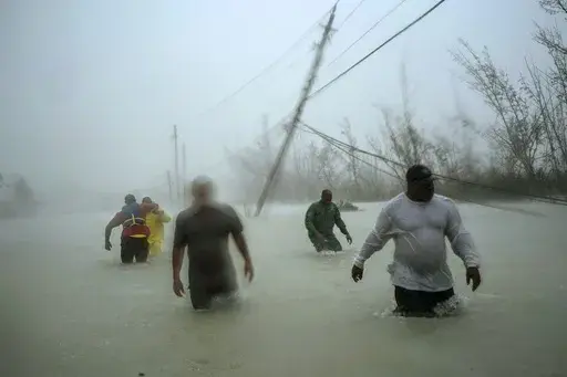 Volunteers wade through a flooded road in the aftermath of Hurricane Dorian to rescue families near the Causarina bridge in Freeport, Grand Bahama, Bahamas, on Sept. 3, 2019. (AP Photo/Ramon Espinosa)