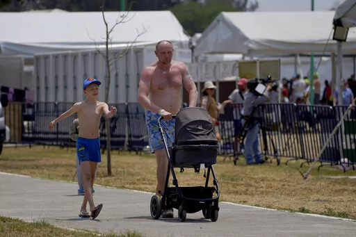 A Ukrainian refugee walks with his children at a camp in Utopia Park, Iztapalapa, Mexico City, Monday, May 2, 2022. (AP Photo/Marco Ugarte)