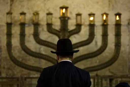 An Ultra-Orthodox Jewish man stands in front of a menorah on the third eve of Hanukkah, at the Western Wall, Judaism's holiest site in Jerusalem's old city, Sunday, Dec. 13, 2009. On eight consecutive nightfalls, Jews gather with family and friends to light one additional candle in the menorah candelabra. They do so to commemorate the rededication of the Temple in Jerusalem in the 2nd century BC, after a small group of Jewish fighters liberated it from occupying foreign forces. (AP Photo/Sebasti