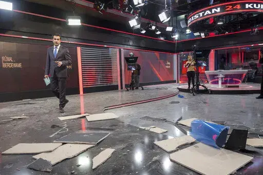 Employees of Kurdistan 24, a satellite television station, work in a studio damaged by an Iranian ballistic missile attack in Irbil, Iraq, Sunday, March 23, 2022. (AP Photo/ Ahmed Mzoori, Metrography)