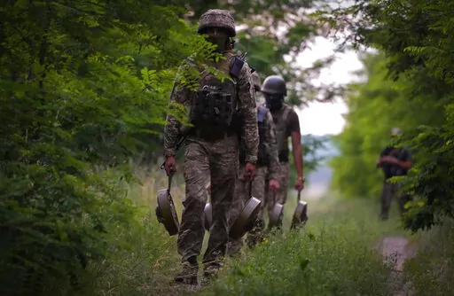 A Ukraine special operations unit carries anti-tank mines to bury on a forest track to prevent Russian troops from advancing toward their trenches, in the Donetsk region, Ukraine,Tuesday, June 14, 2022. (AP Photo/Efrem Lukatsky)